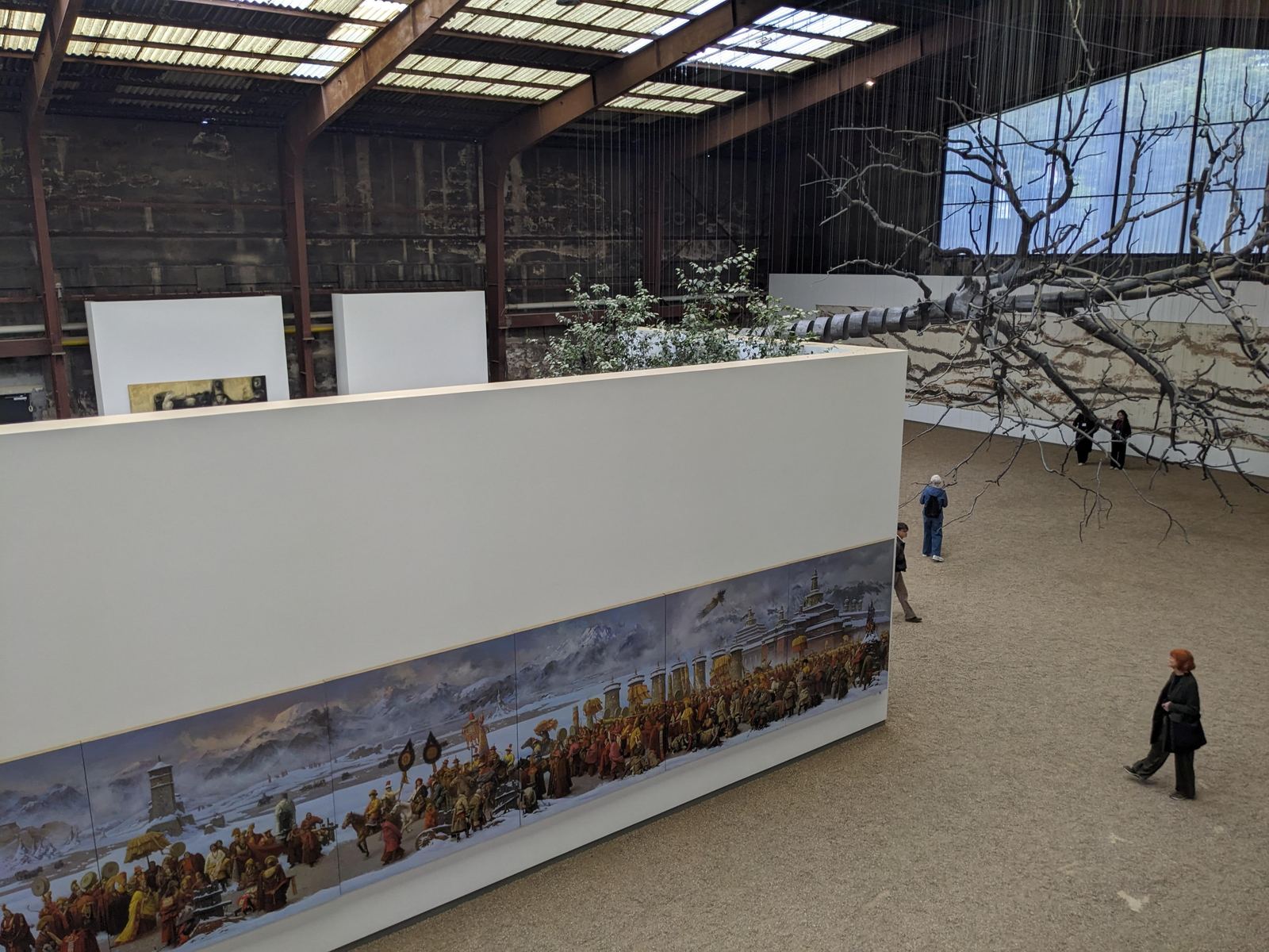 Weitere Ansicht der Halle mit dem hängenden Astwerk und einer mehrteiligen gemalten Prozessionsszene in winterlicher Berglandschaft an einer Zwischenwand