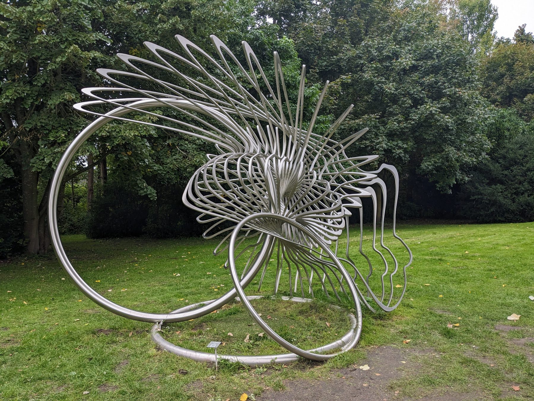 Gesamtansicht der Edelstahlskulptur Shell von Jan Dostál auf einer Rasenfläche.