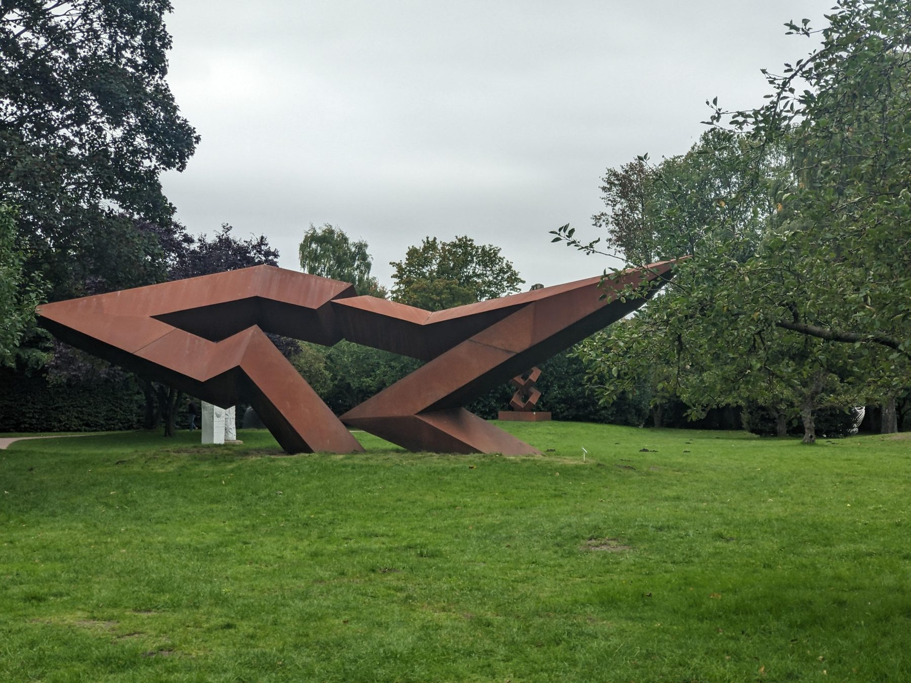 NordArt Büdelsdorf - Dialogue Beyond Borders von Jörg Plickat als weit ausgreifende Cortenstahl-Skulptur im Park.