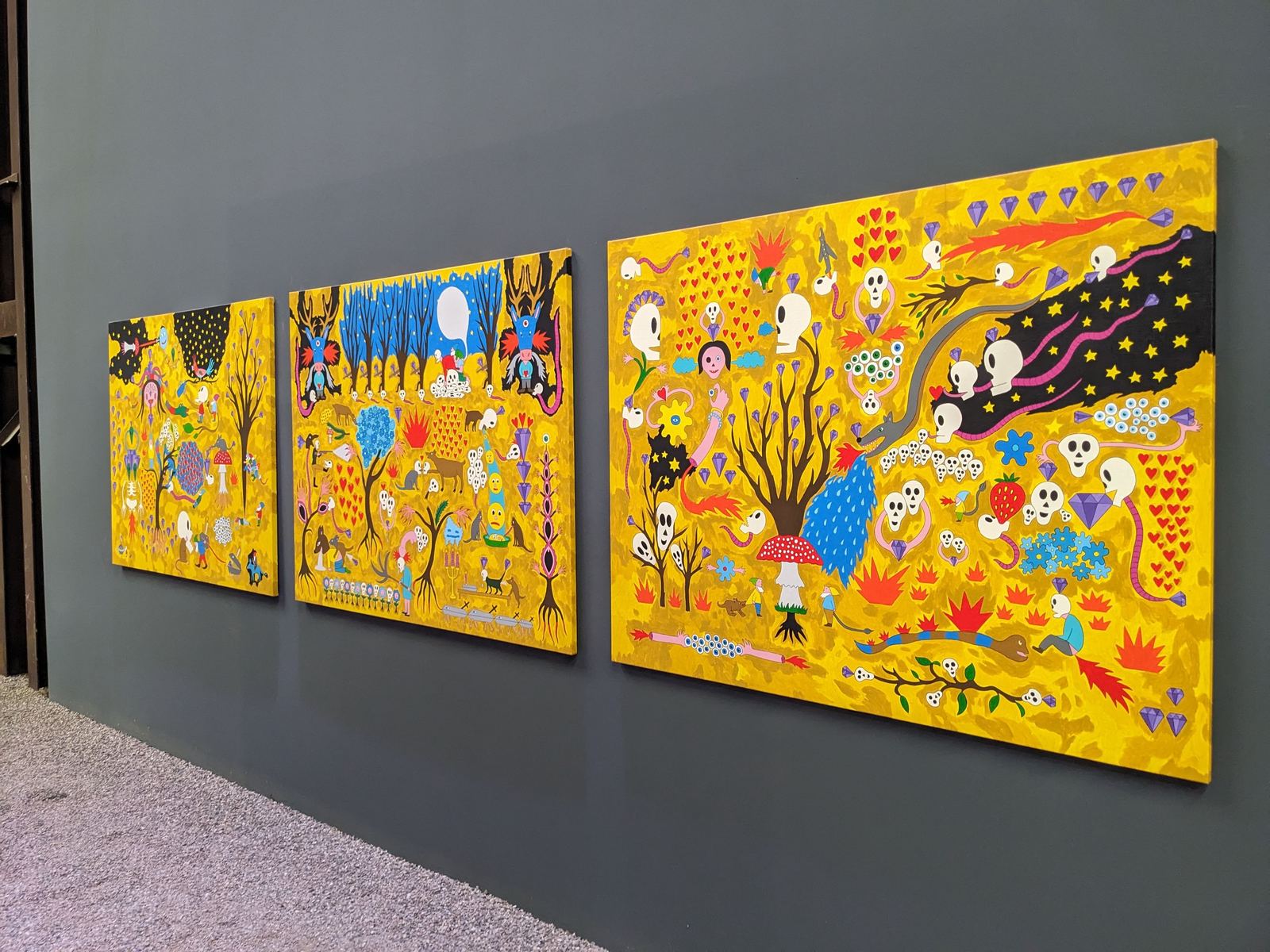 Dreiteiliges gelbes Wandbild „Star War of Diamonds“ von Marko Mäetamm, dicht bemalt mit Totenköpfen, Herzen, Bäumen und Diamanten, in der Ausstellungshalle der Carlshütte