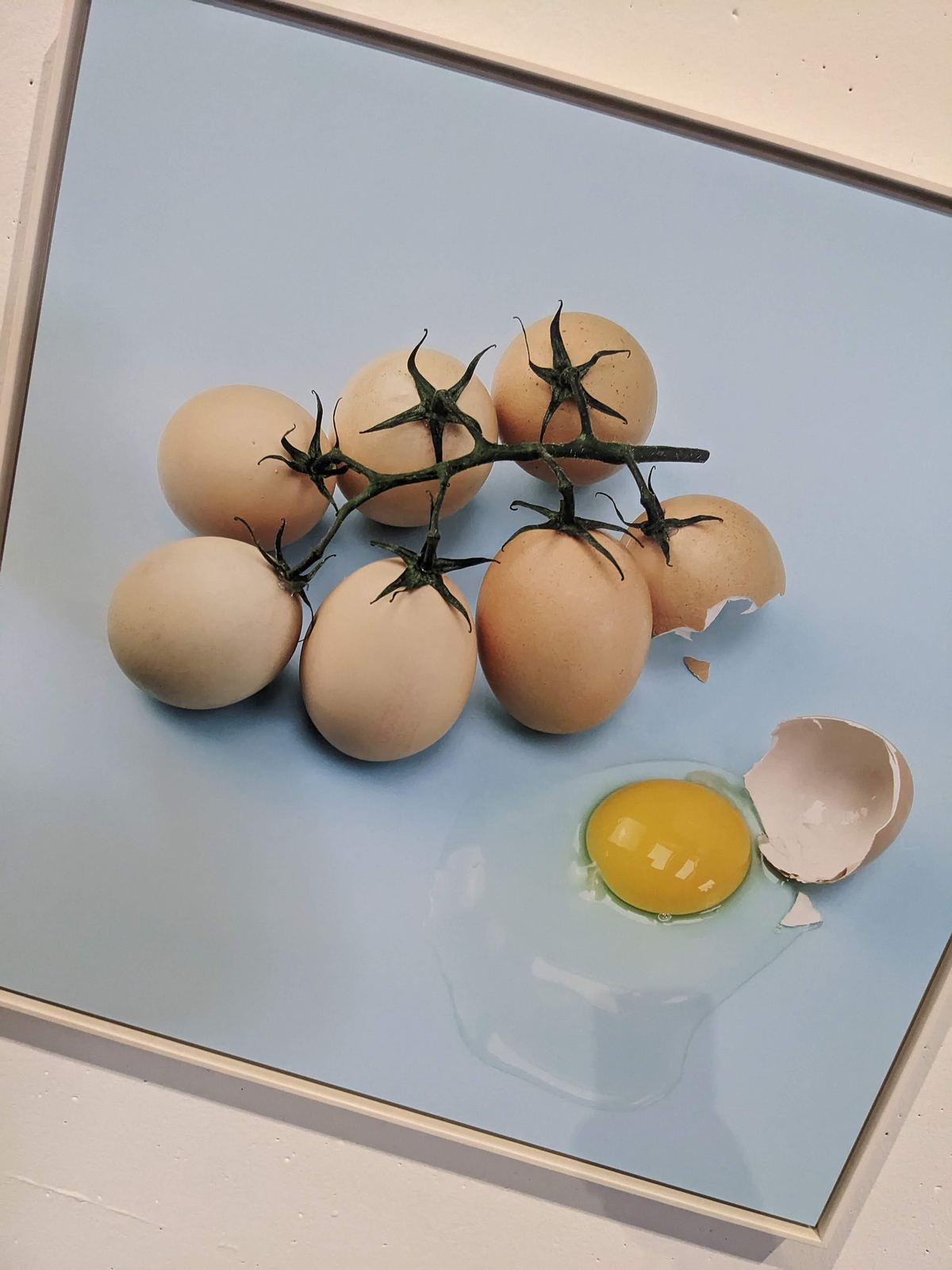Rispentomaten, bei denen die Tomaten durch braune Eier ersetzt wurden, davor ein aufgeschlagenes Ei mit Dotter
