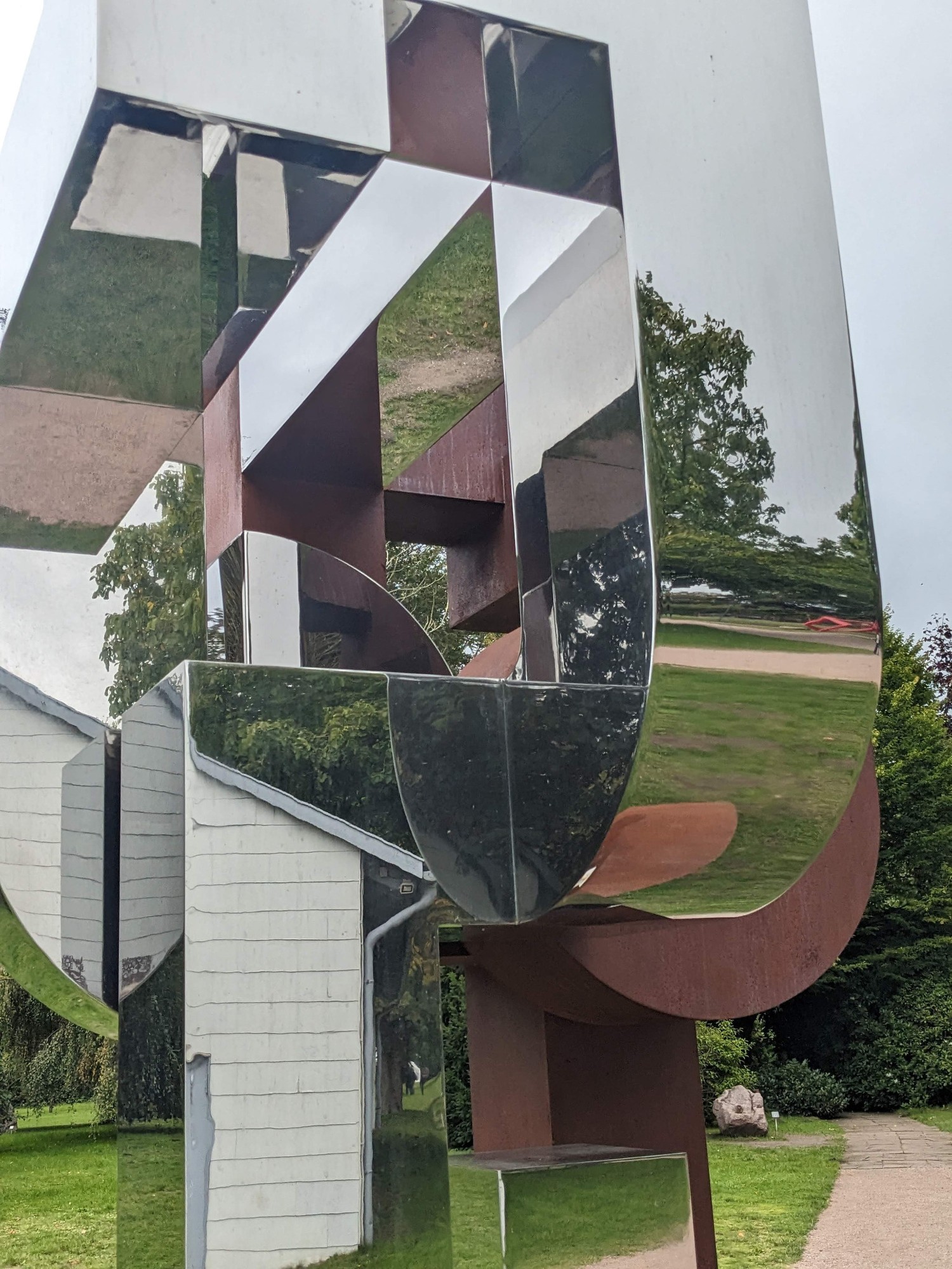 Detail der spiegelnden Edelstahlflächen von Zhu Lins Skulptur Great Heat mit Reflexionen der Umgebung.
