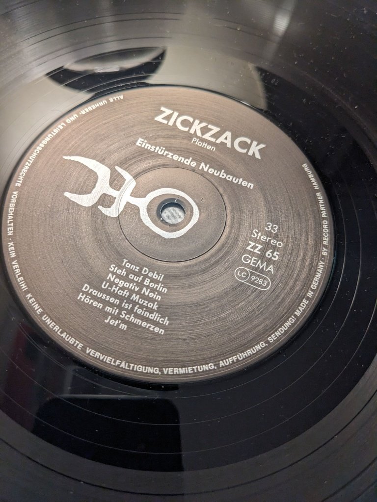 Schwarze Schallplatte von Einstürzende Neubauten auf dem Plattenspieler mit ZickZack-Label.