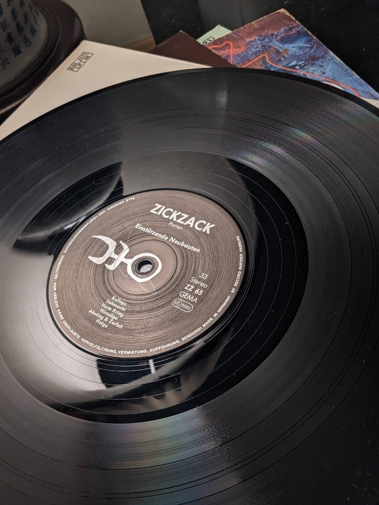 Nahaufnahme des Plattenlabels von Seite A mit Trackliste von Tanz Debil bis Jet'm und ZickZack Platten Logo.