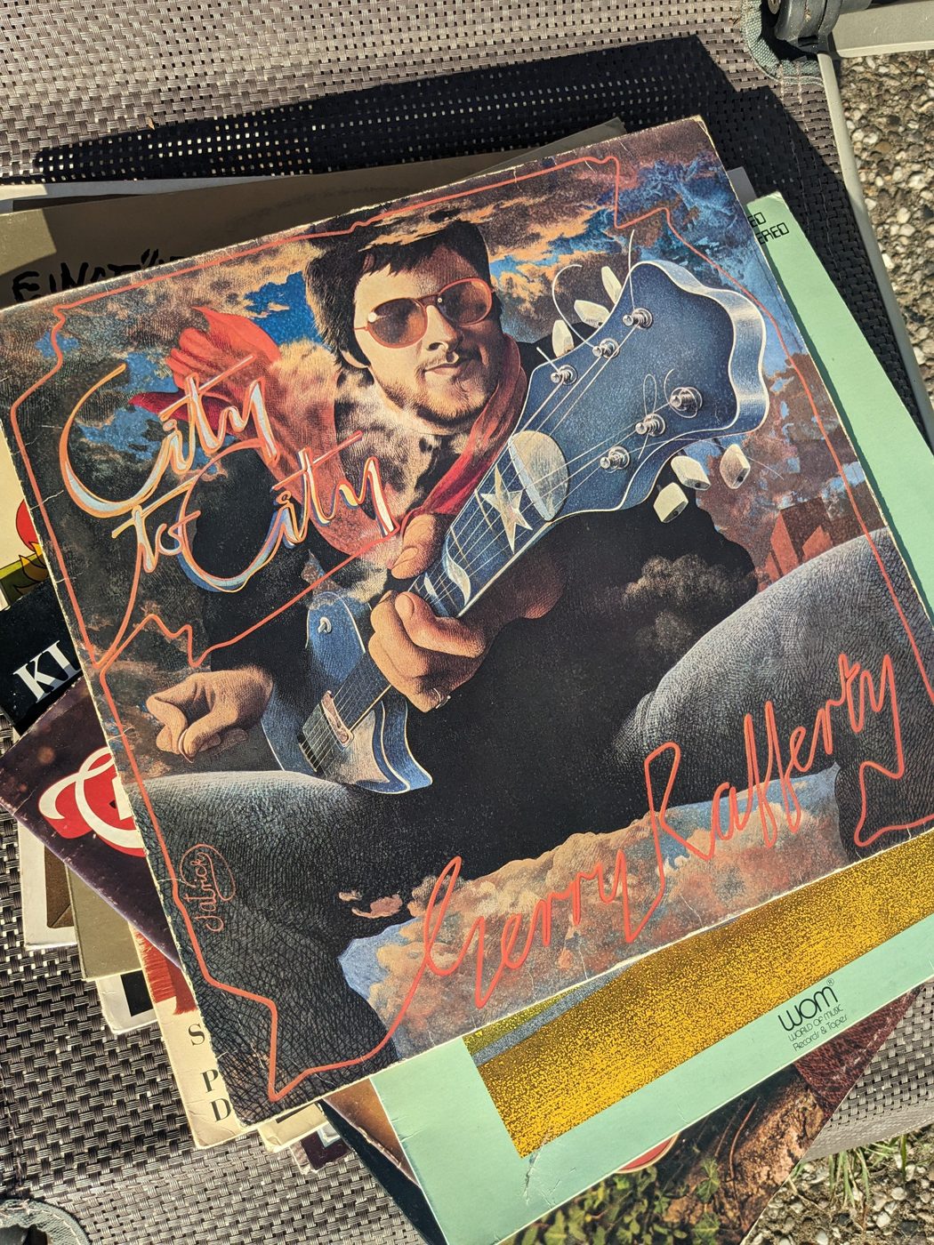 Gerry Rafferty – City to City, Vorderseite der LP-Hülle mit illustriertem Gerry Rafferty mit Sonnenbrille und blauer Gitarre