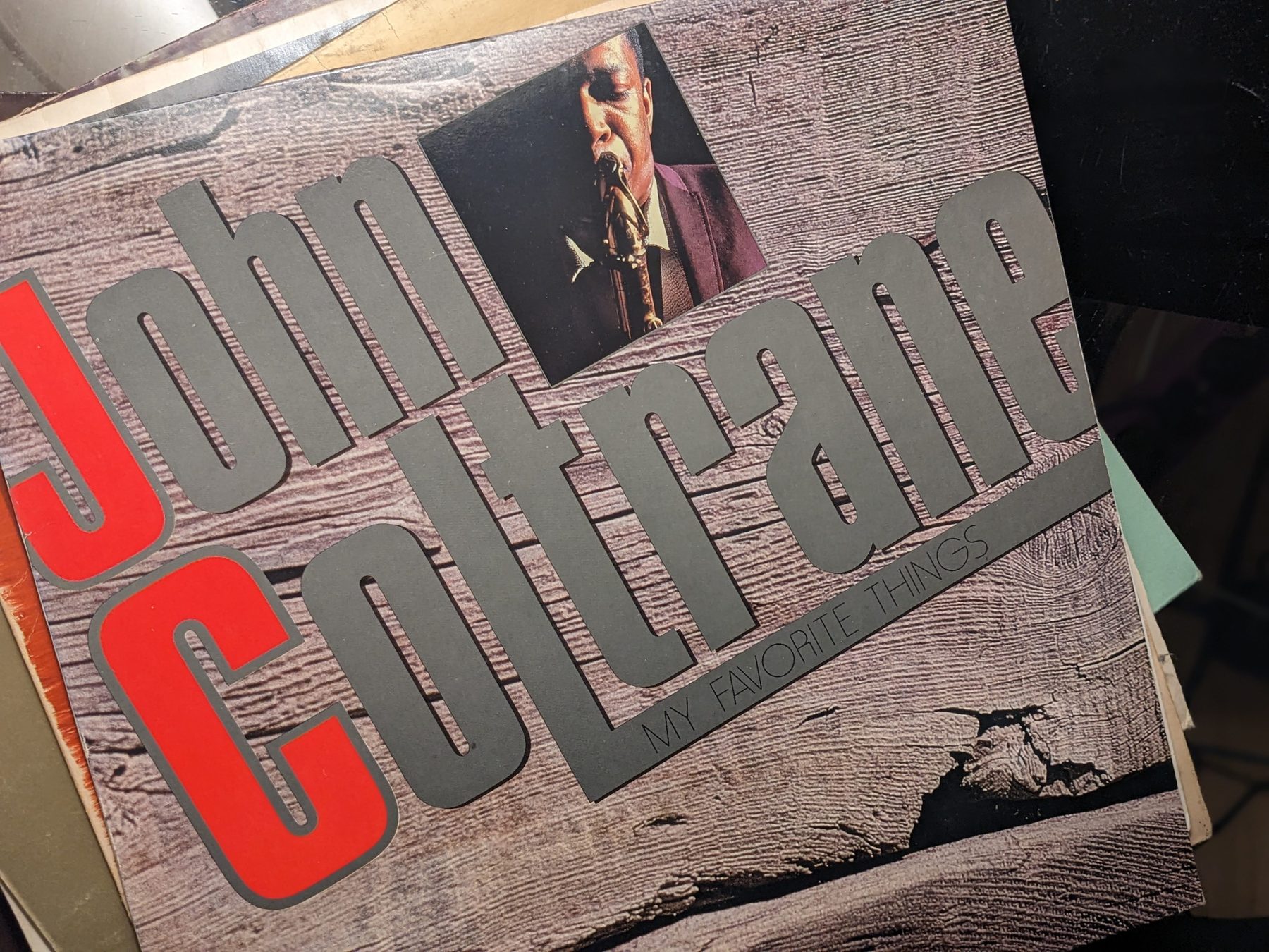 John Coltrane Schallplatte– My Favorite Things: Frontcover der Schallplatte mit Holzmaserungs-Gestaltung, großer grauer und roter Typografie und kleinem Foto eines Saxofonisten.