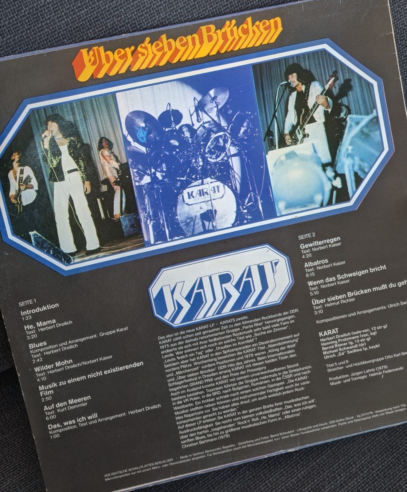 Schallplattenhülle der Band Karat. Oben steht in geschwungener orange-gelber Schrift 'Über sieben Brücken'. Darunter ist ein achteckiges Bühnenfoto der fünf Bandmitglieder bei einem Konzert zu sehen. Links und rechts daneben stehen die Titel der Seiten 1 und 2. Unten prangt das blau-weiße Karat-Logo über einem ausführlichen Begleittext und Besetzungsangaben.