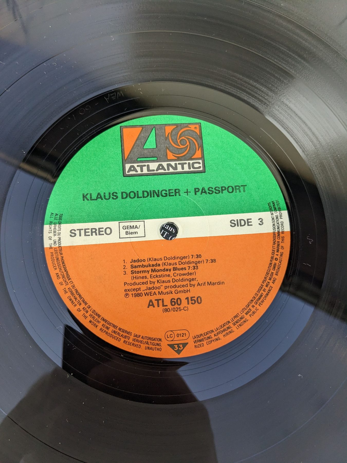 Nahaufnahme einer schwarzen Vinylplatte mit grün-orangefarbenem Atlantic-Label, Aufschrift Klaus Doldinger + Passport, Side 3 und Katalognummer ATL 60 150.