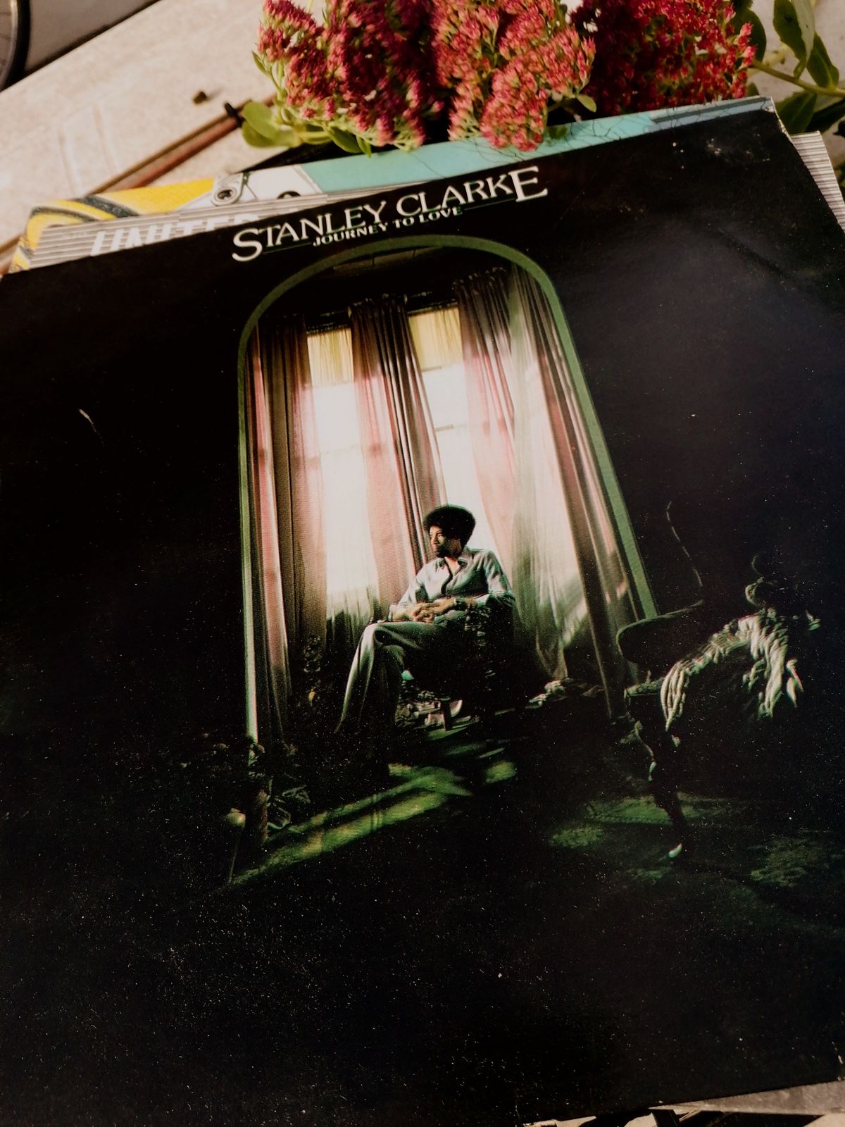 Cover der Fusion-LP / Jazzrock Schallplatte Journey to Love von Stanley Clarke: Ein Mann sitzt in einem Bogenfenster vor hellen Vorhängen