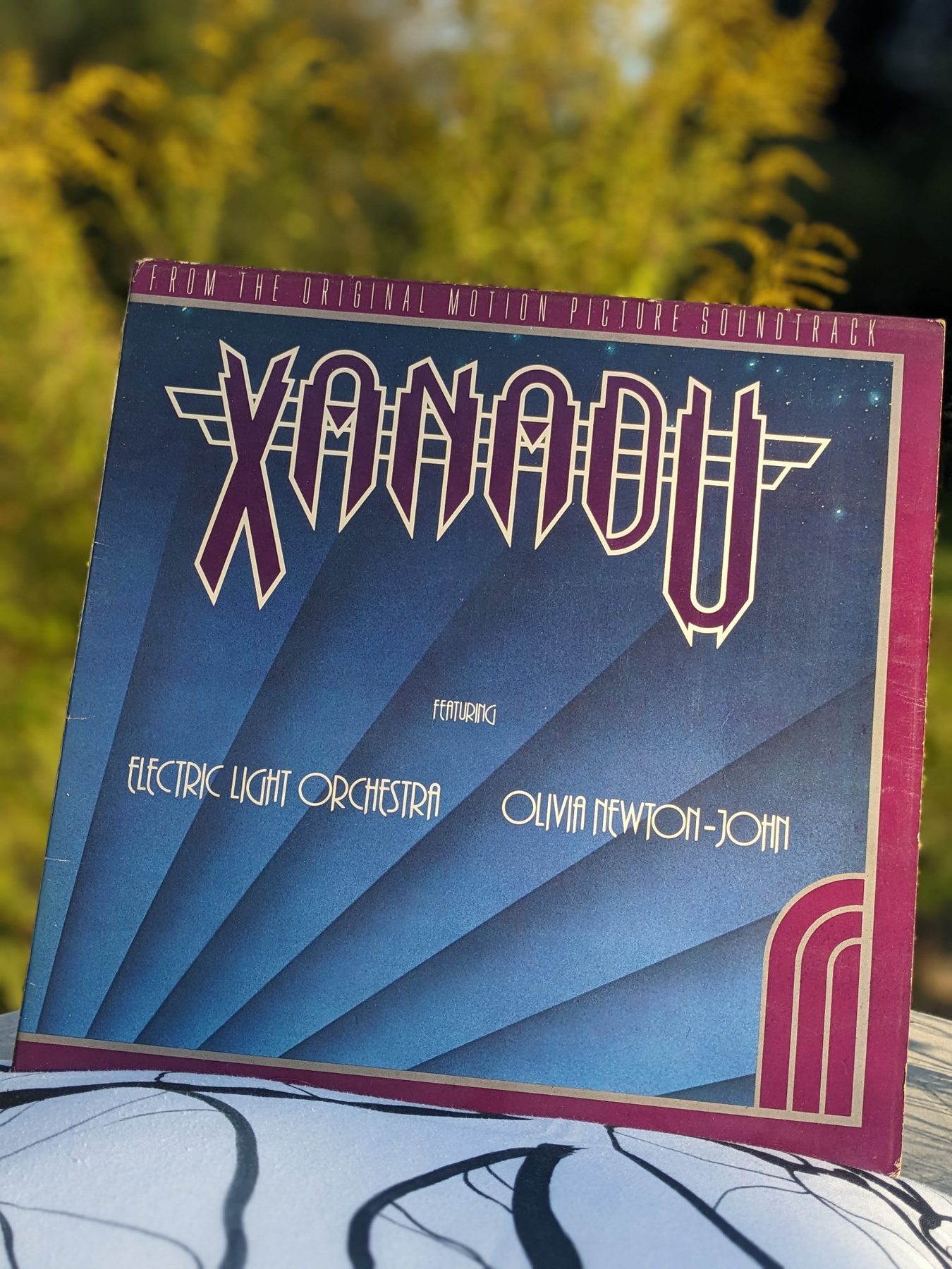 Vorderseite des blauen und violetten Xanadu-Soundtrackcovers im Freien, mit großem Xanadu-Schriftzug sowie den Namen Electric Light Orchestra und Olivia Newton-John.